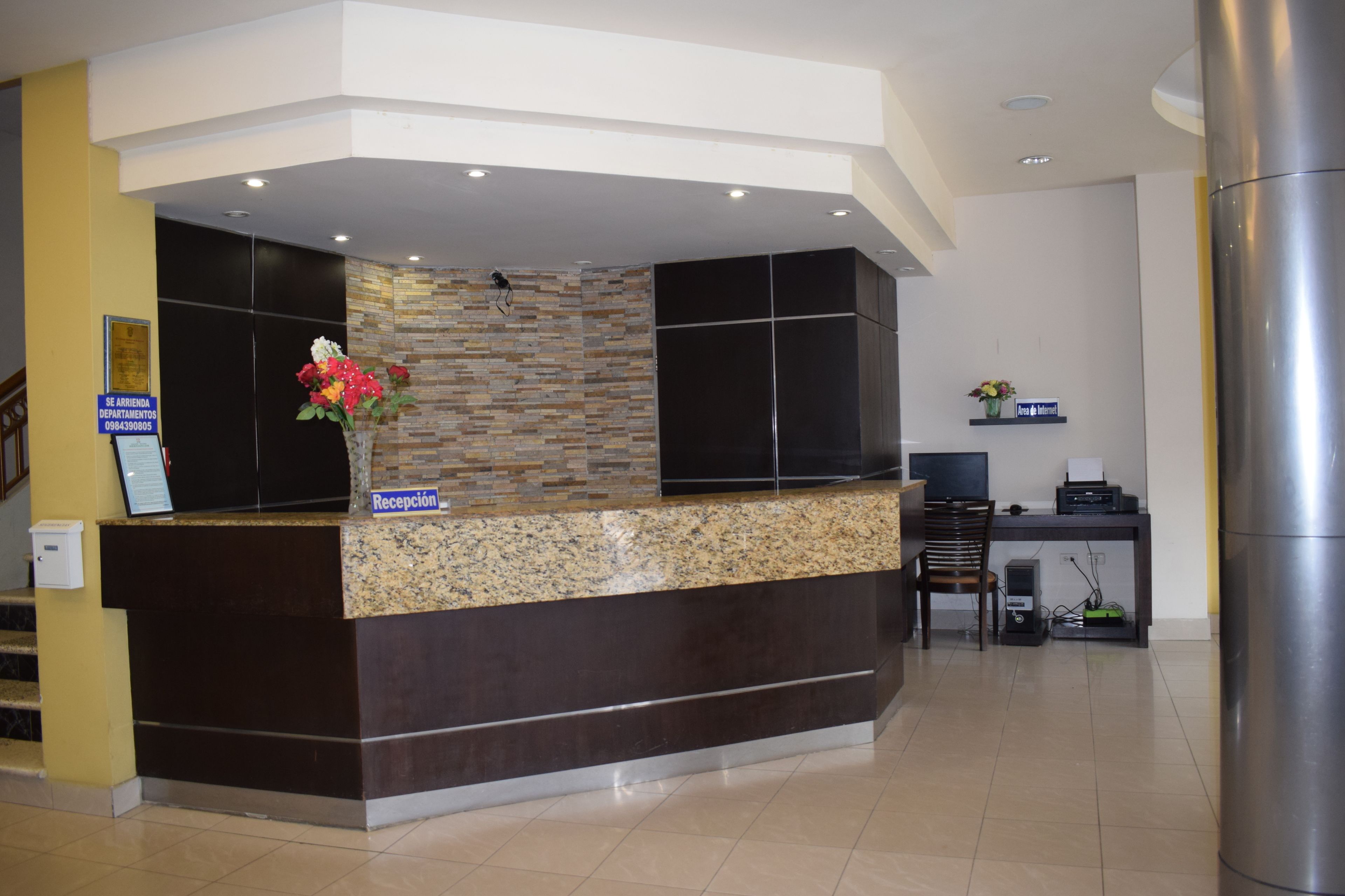 A reception area with a stone wall, a reception desk, a computer, and a chair.