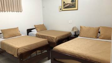 Habitación de hotel con tres camas, un cuadro en la pared, un equipo de aire acondicionado y una cortina.