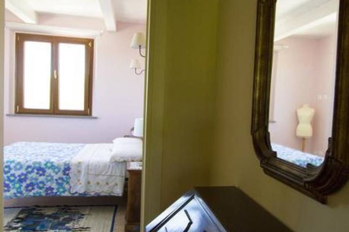 A bedroom with a bed, a dresser, a mirror, and a window.