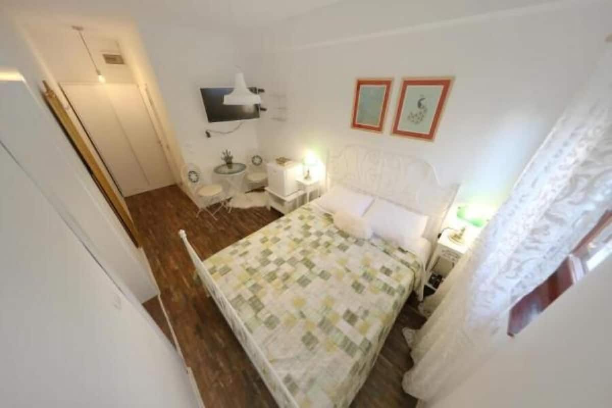 A bedroom with a bed, bedside tables, a desk, and a chair.