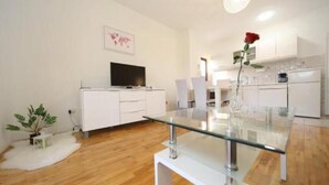A modern kitchen with white cabinetry, a glass dining table, and a rose on the table. - Ina Apartments (Zadar)