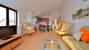 A modern living room with a TV, sofa, and coffee table. A dining area with chairs and a table is visible in the background. - Ina Apartments (Zadar)