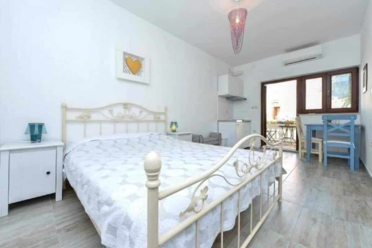 A bedroom with a bed, bedside table, and a chair.