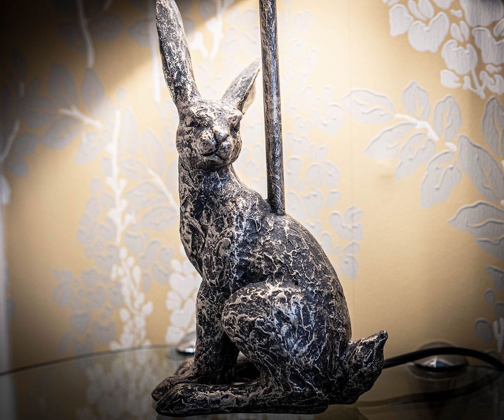 Une sculpture métallique représentant un lapin, posée sur une table en verre.