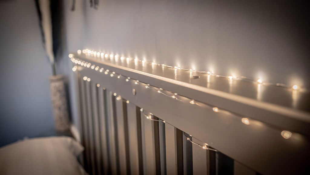 A close-up of a white radiator with a string of lights wrapped around it.