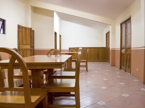 A dining area with wooden tables and chairs, a tiled floor, and wooden doors. - OYO Hotel Museo (Xalapa)