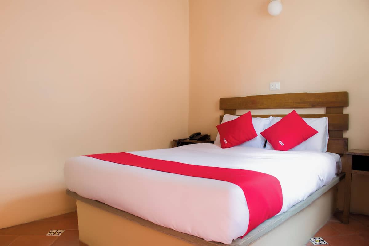 A bed with a wooden headboard, white bedding, and red pillows.