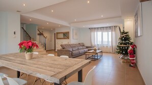 Un vaste espace de vie comprenant une table à manger en bois, un canapé et un sapin de Noël.
