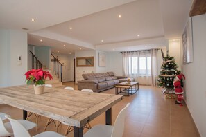 A spacious living area with a wooden dining table, a sofa, and a Christmas tree.