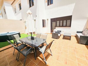 A patio with a glass table and chairs, a sofa, and a small table. - RONDA HOME, BEAUTIFUL MODERN HOUSE + WIFI (Ronda)