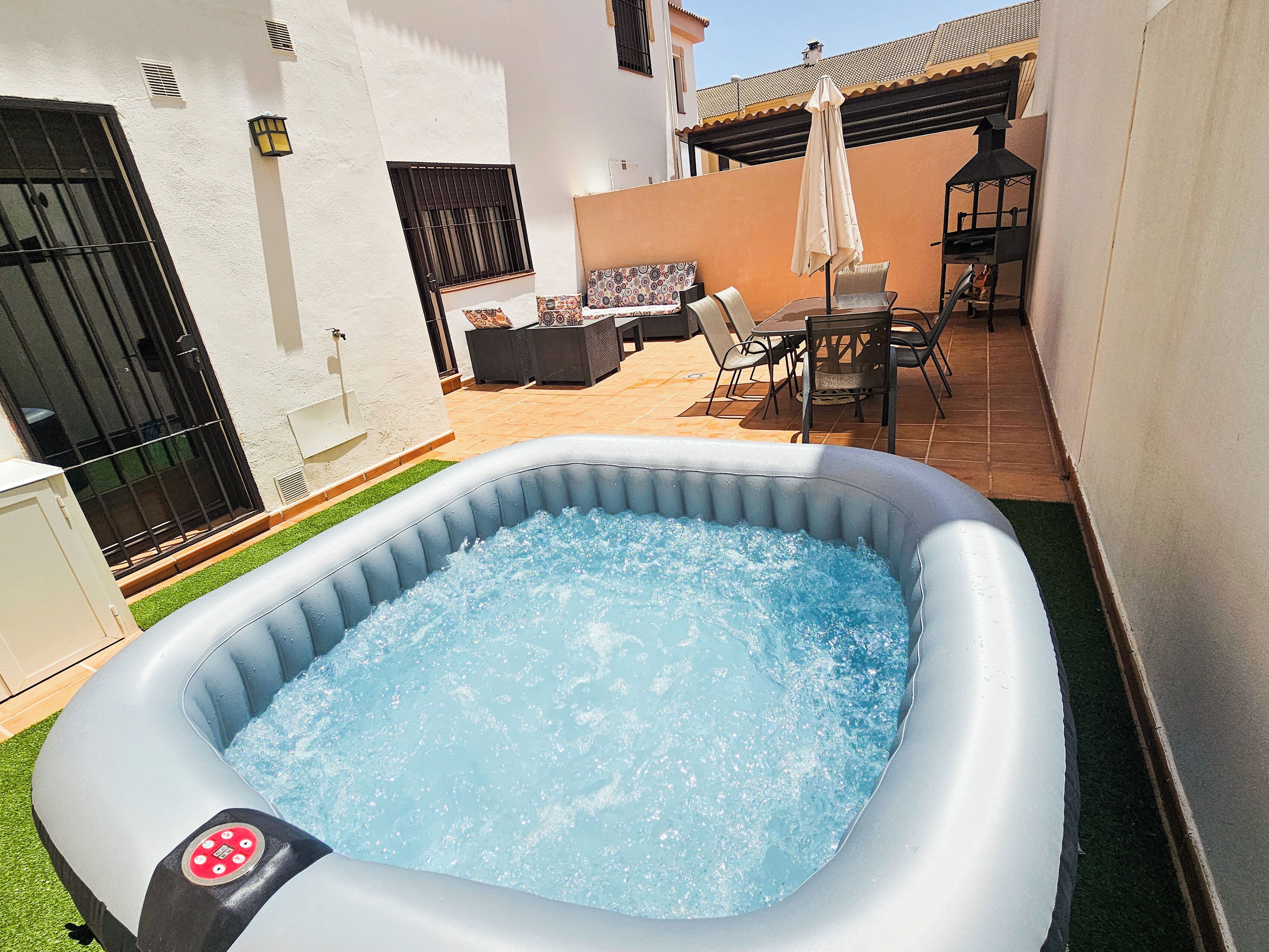 An inflatable hot tub in a backyard with a patio area, outdoor furniture, and a view of the surrounding buildings.