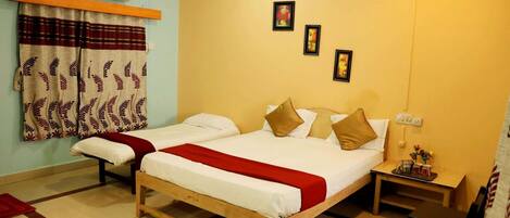 A room with two wooden beds, a small table with a vase, and a wall-mounted air conditioner.