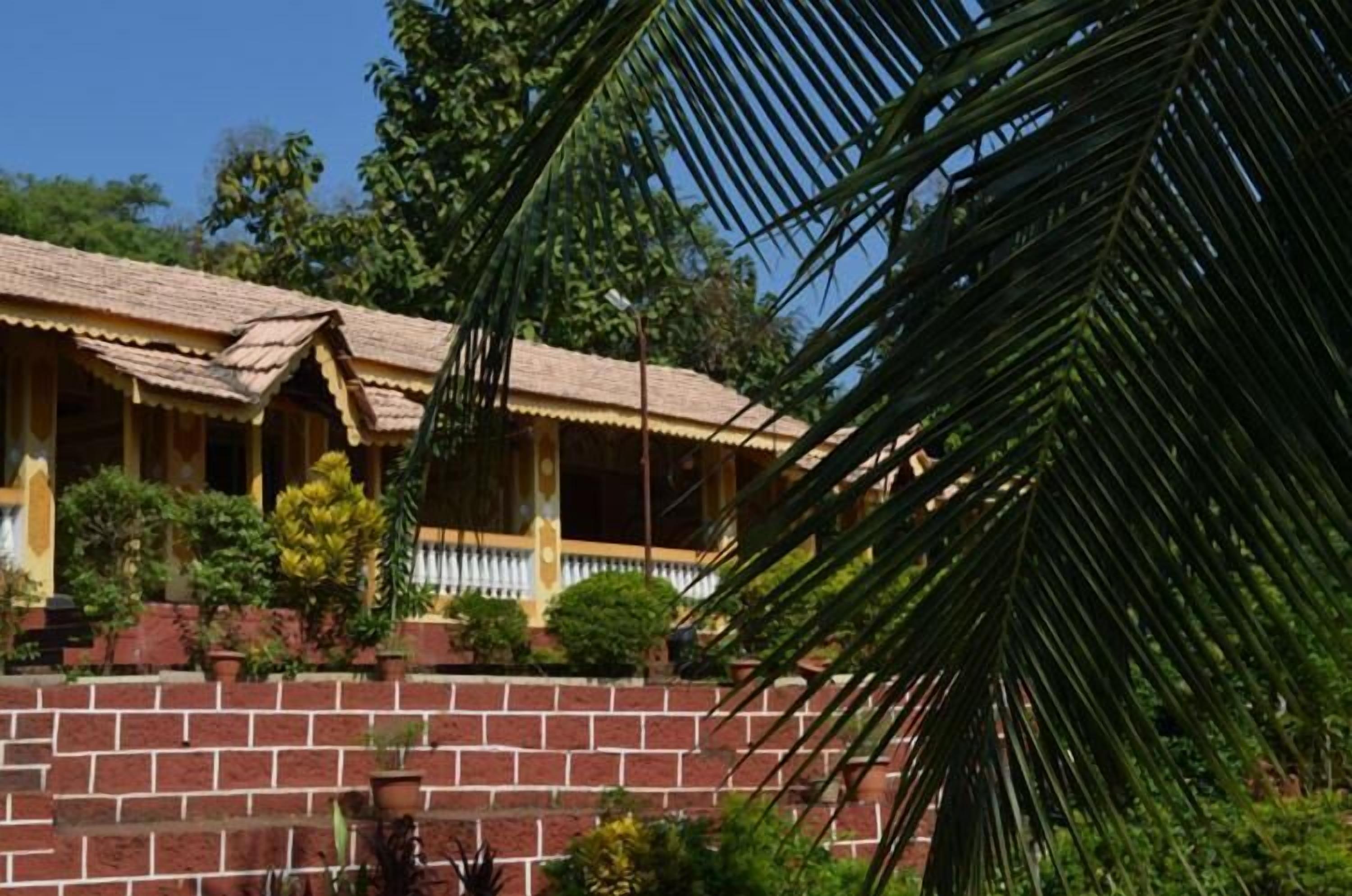 A traditional house with a tiled roof, a brick wall, and a small porch with railings.