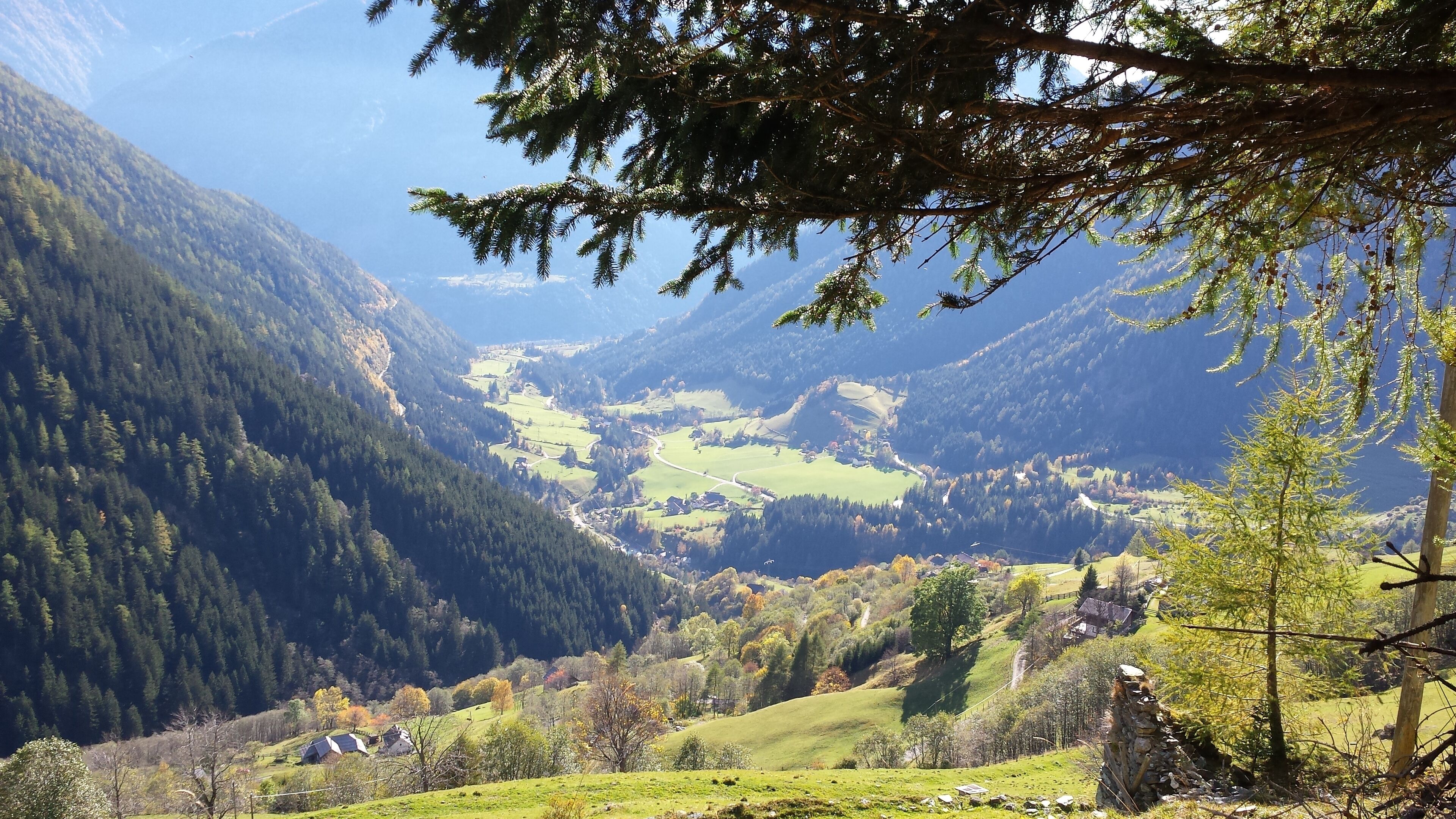 Eine gebirgige Landschaft mit einem Tal, Häusern und einem bewaldeten Gebiet.