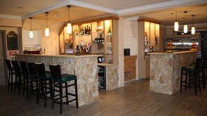 A bar area with multiple seating options, a well-stocked bar counter, and hanging pendant lights. - Hotel Mallnitz Appartements (Mallnitz)