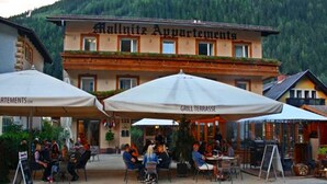 A building with the sign 'Mallnitz Apartments' and outdoor seating with umbrellas. - Hotel Mallnitz Appartements (Mallnitz)