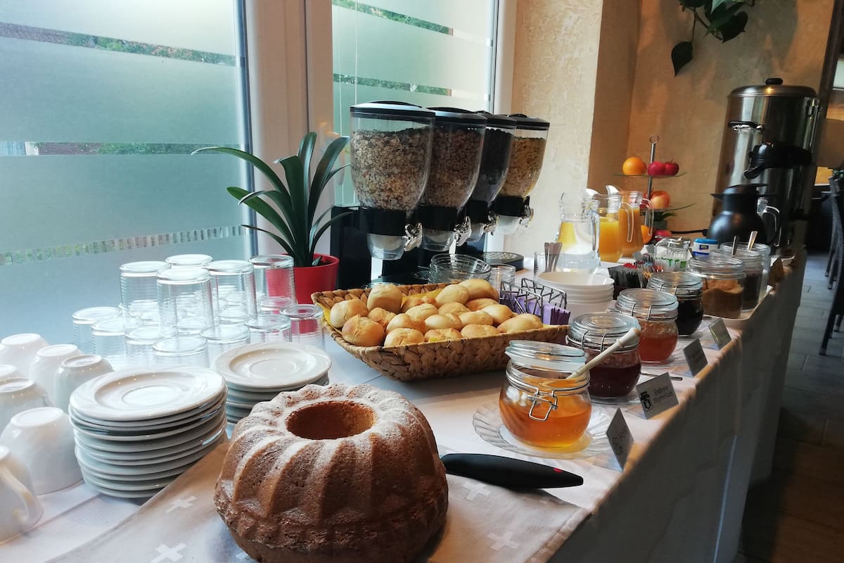 Montaje de bufé con diversos alimentos, entre ellos, un pastel bundt, panes y frascos con condimentos.