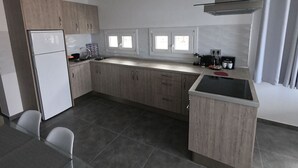 Una cucina moderna con frigorifero, lavello doppio e un piccolo angolo ristoro con sedie.