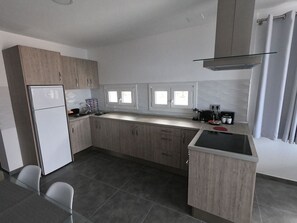 Une cuisine moderne équipée d’un réfrigérateur, d’un évier à deux bacs et d’un petit coin repas avec des chaises.