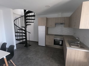 Une cuisine compacte dotée d’un four encastré, d’un évier et d’un escalier en colimaçon.