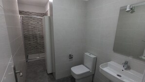 A bathroom with a toilet, sink, and shower area.