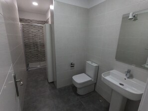 Un baño con inodoro, lavamanos y zona de ducha.