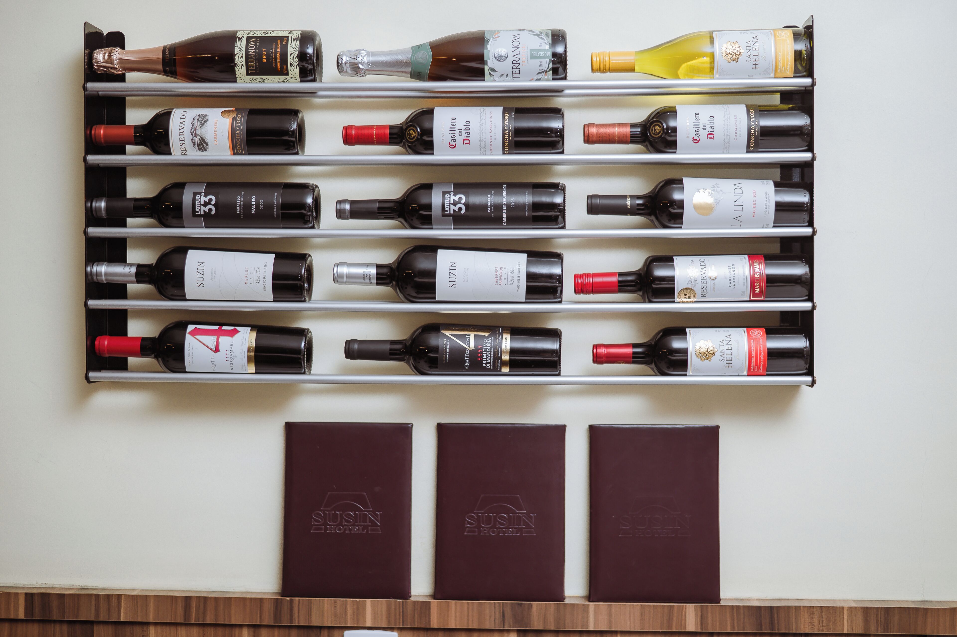 A wine rack with various bottles and three branded boxes.