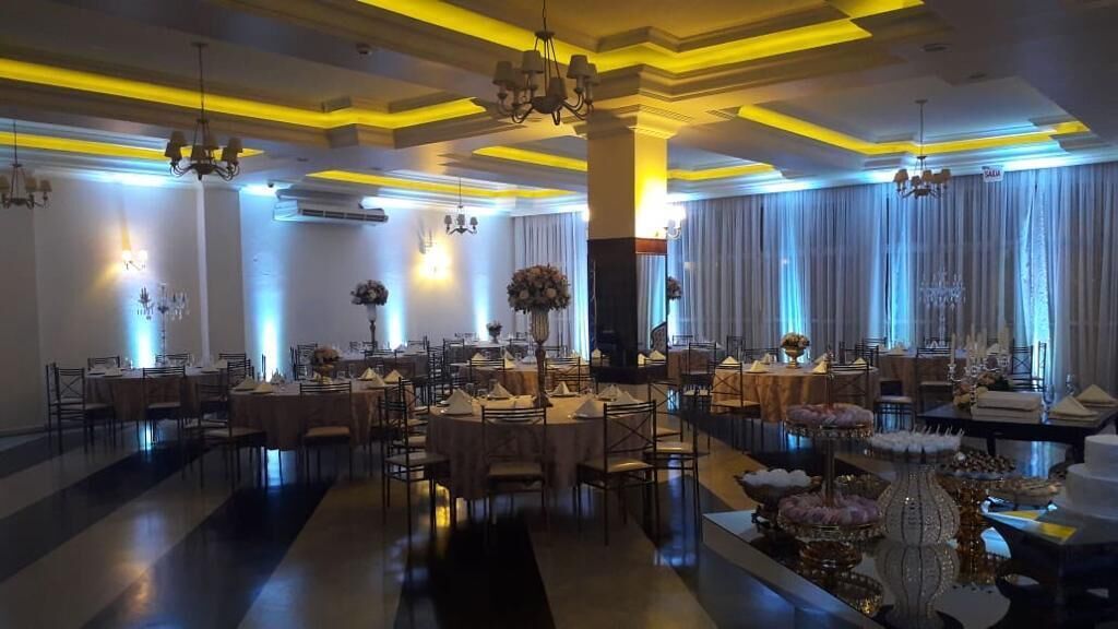 A banquet hall with round tables, chandeliers, and a reflective floor.