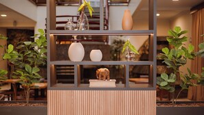 A modern interior with a wooden panel wall, a glass shelf with decorative items, and potted plants. - Susin Hotel (Mafra)