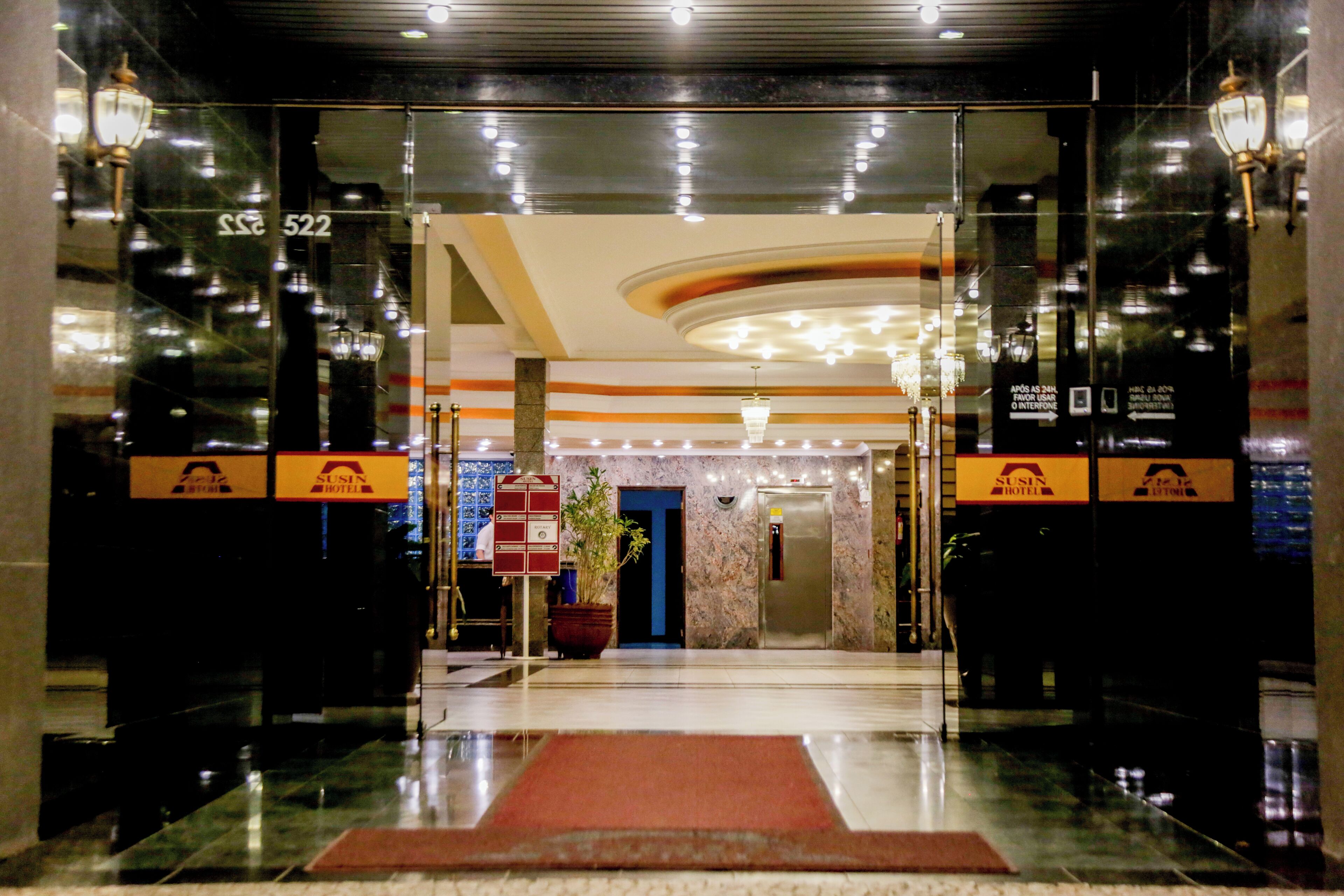 Vestíbulo de hotel con suelo de mármol, alfombra roja y mostrador de recepción.
