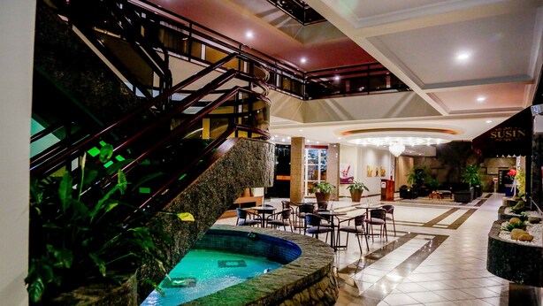 A hotel lobby with a central pool, a staircase, and seating areas. - Susin Hotel (Mafra)