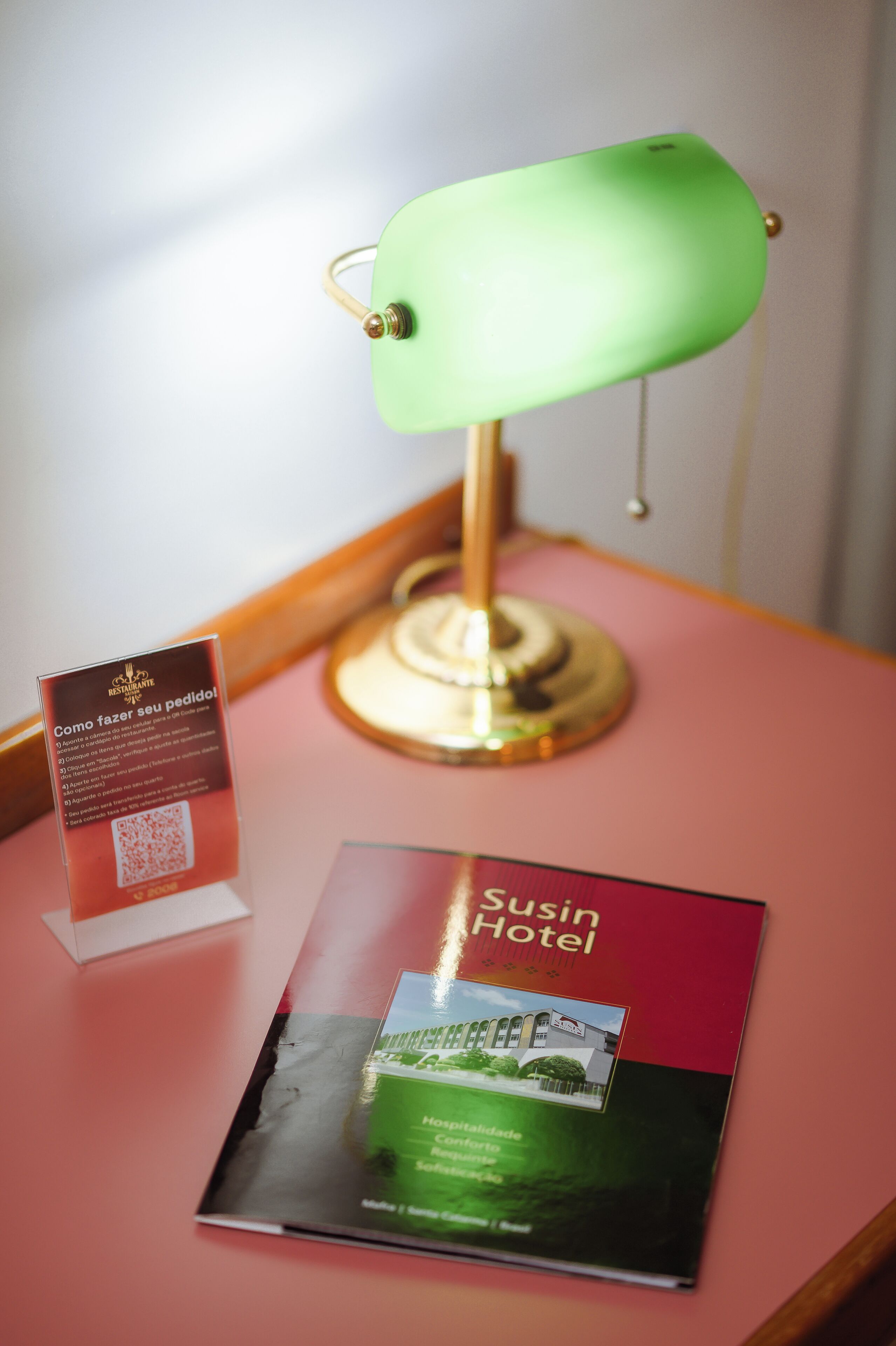 Um folheto do Hotel Susin com uma luminária de mesa verde e uma placa com instruções.