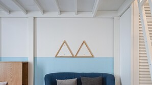 Un salón moderno con un sofá azul, una mesa de centro de madera y un adorno geométrico en la pared.