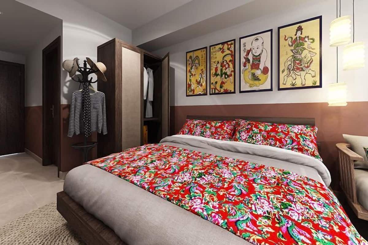 A modern bedroom with a large bed, a wardrobe, and three framed artworks on the wall.