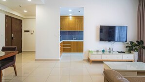 Una sala de estar moderna con televisor, zona de comedor y cocina con armarios de madera.