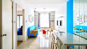 Una sala moderna con un sofá azul, una mesa de comedor y una zona de cocina.