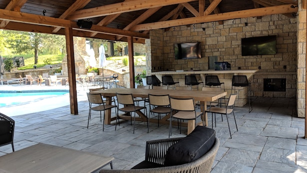 Un patio al aire libre con chimenea de piedra, piscina y mobiliario exterior.