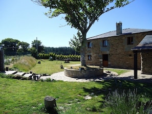 A stone building with a circular stone patio, a tree, and a well-maintained lawn. - Rigueira House in Cospeito (Cospeito)