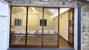 A classroom with a stone wall, large windows, and a wooden door.