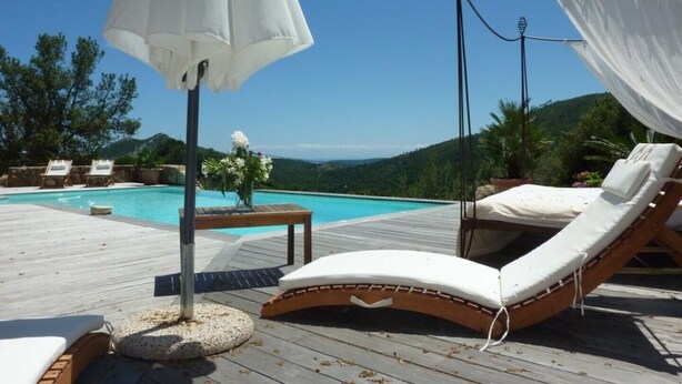Une terrasse en bois avec une piscine, des chaises longues et un auvent.