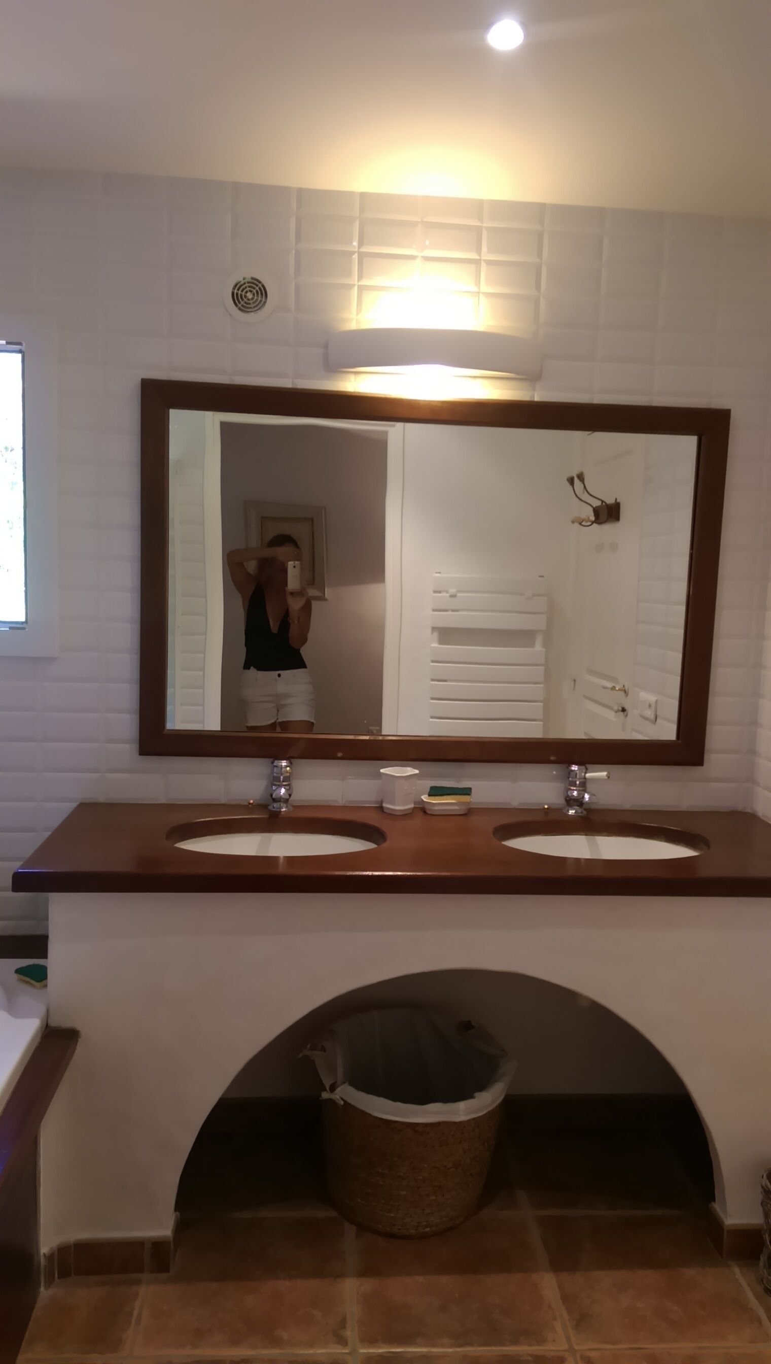 Un baño con dos lavamanos, un espejo grande y un perchero para toallas.