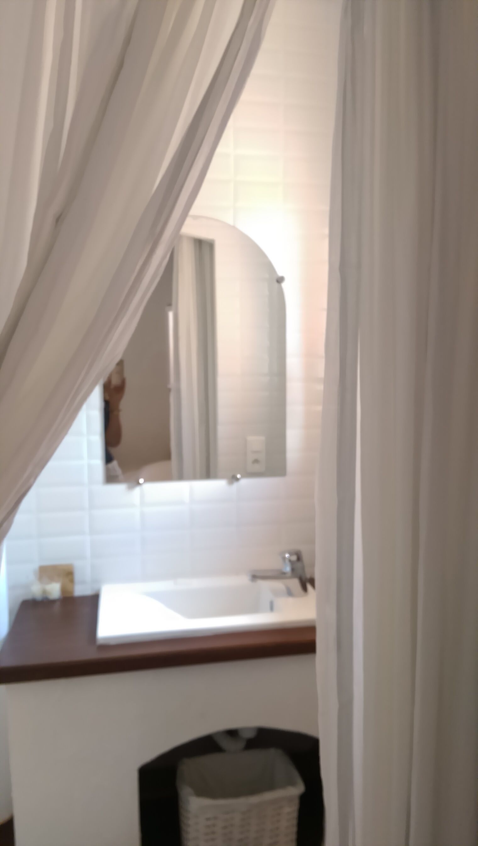 Un bany amb un lavabo blanc, un mirall i una zona de dutxa.
