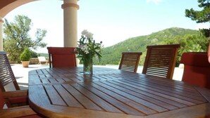 Une table en bois avec des chaises, un vase de fleurs et une vue sur une montagne.