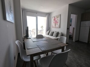 A modern dining area with a table, chairs, and a sofa.