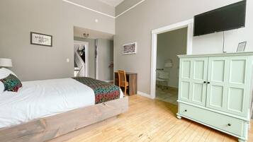 Un dormitorio con cama, armario, televisión y puerta al baño.