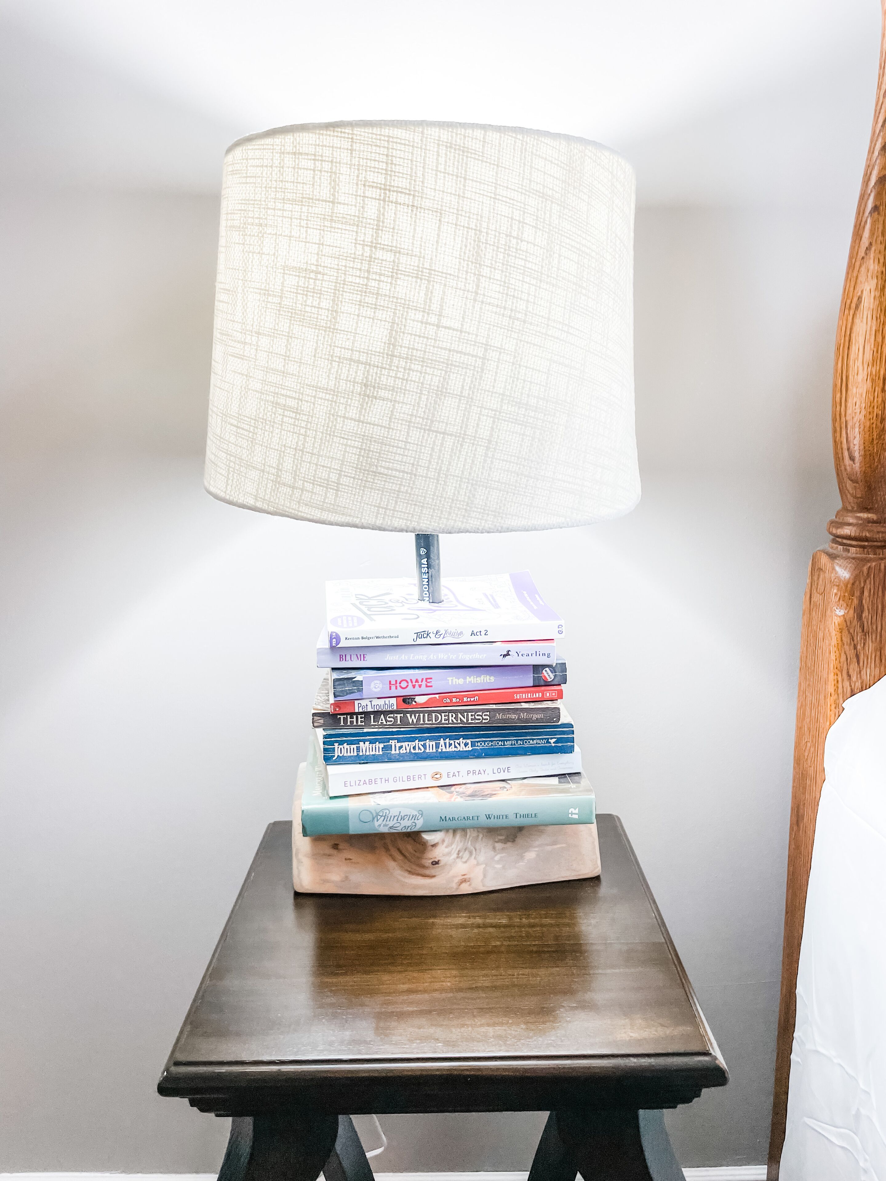 Un comodino con una lampada e una pila di libri.