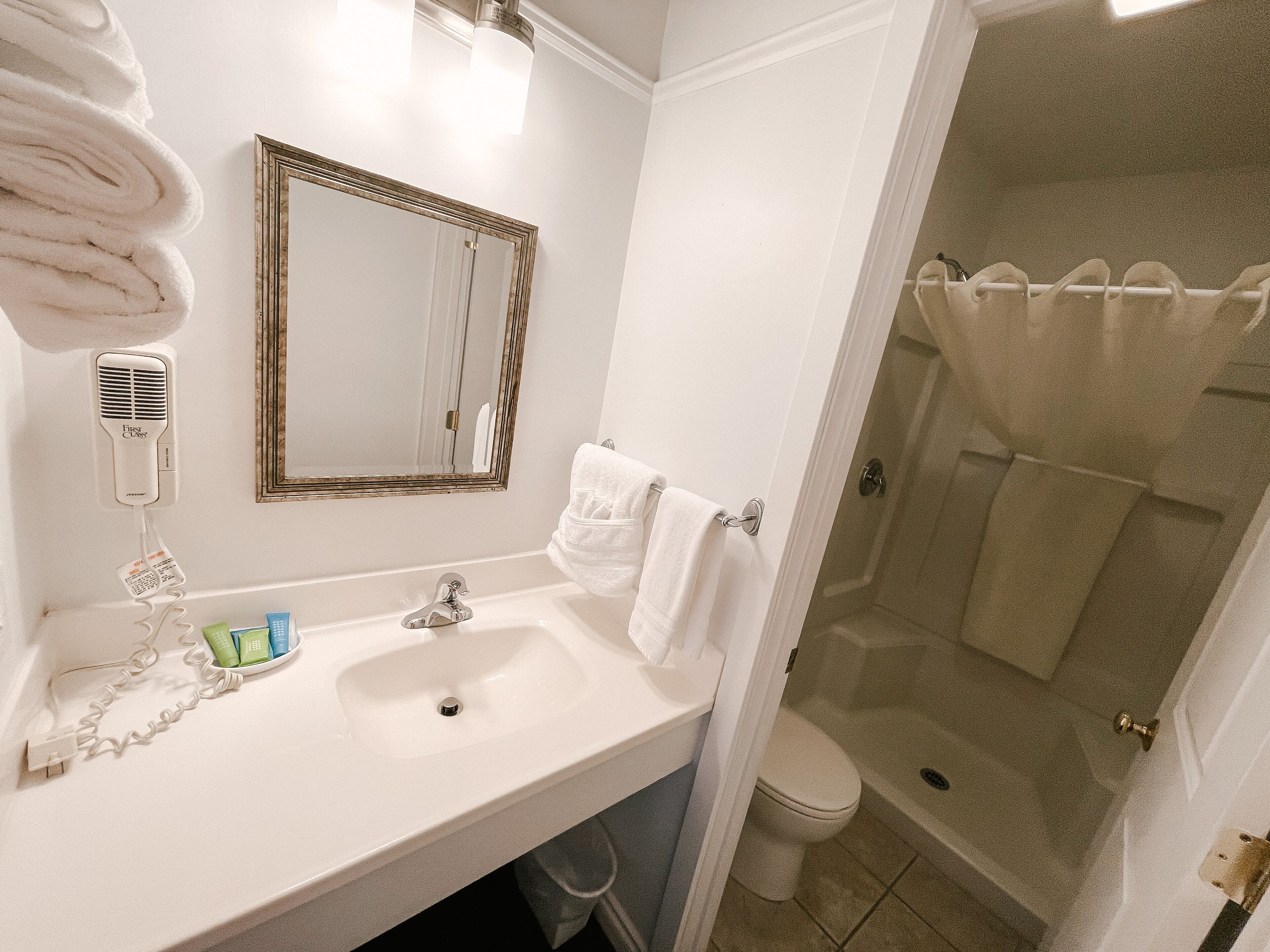 Un baño con lavamanos, espejo, toallero y zona de ducha.