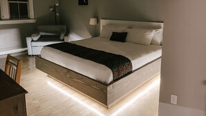 A neatly arranged bedroom with a large bed, a chair, and a bedside table. - Northside School B&B (Bonners Ferry)