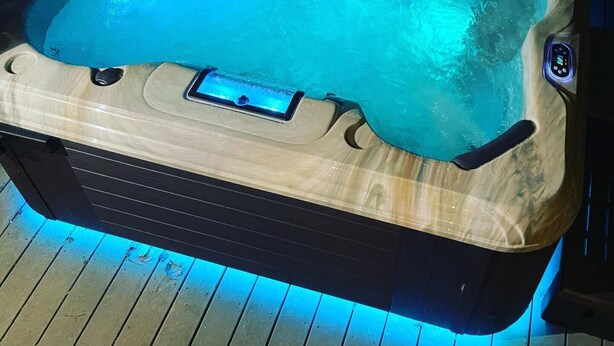 A hot tub with a control panel on the side, surrounded by wooden decking. - Northside School B&B (Bonners Ferry)