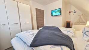A bedroom with a bed, a TV, a wardrobe, and a mosquito net.